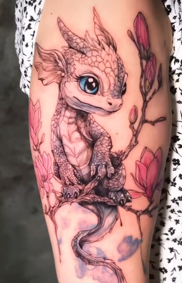 Tattoo eines niedlichen Drachen mit blauen Augen, der auf einem Ast sitzt, umgeben von Blumen.